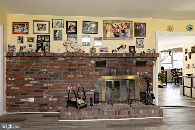 detailed view of wood finished floors, crown molding, and a brick fireplace
