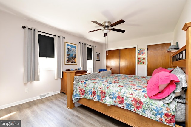 bedroom with wood finished floors, multiple closets, baseboards, and ceiling fan