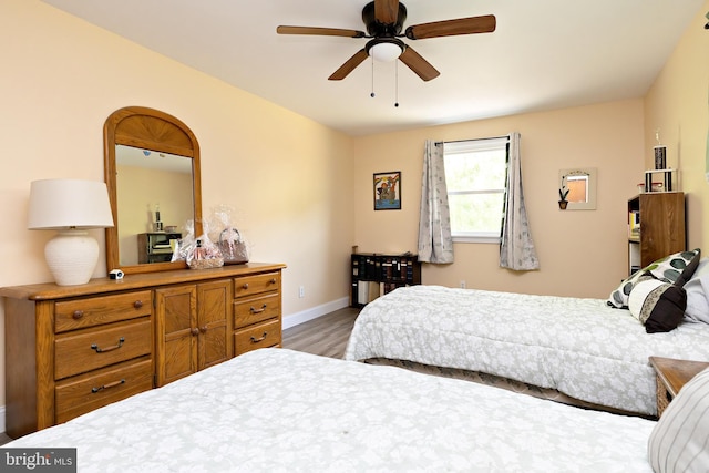 bedroom featuring wood finished floors, baseboards, and a ceiling fan