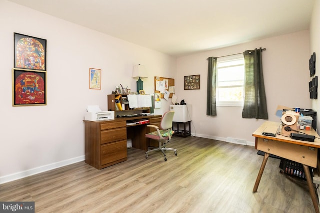 home office with light wood-style flooring and baseboards