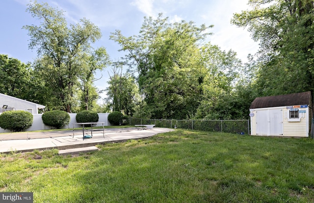 view of yard featuring a shed, a patio area, an outbuilding, and view of wooded area