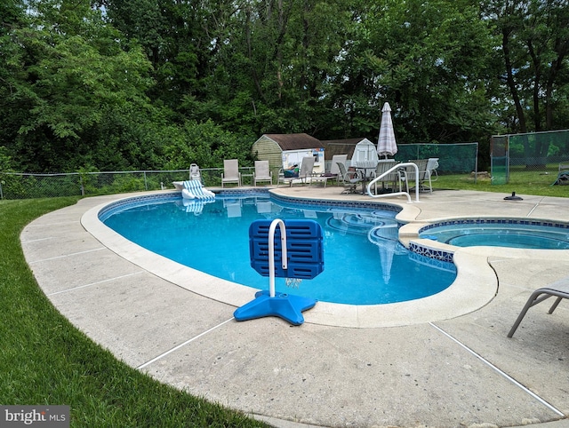 view of swimming pool with a storage shed, fence, a patio, an outdoor structure, and a pool with connected hot tub