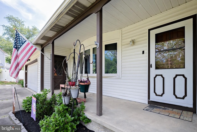 view of exterior entry featuring a porch and a garage