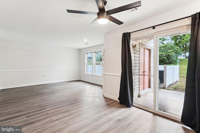 spare room with baseboards, a ceiling fan, visible vents, and wood finished floors
