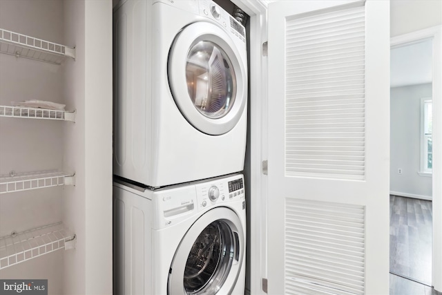 laundry area featuring laundry area, stacked washer and clothes dryer, and wood finished floors