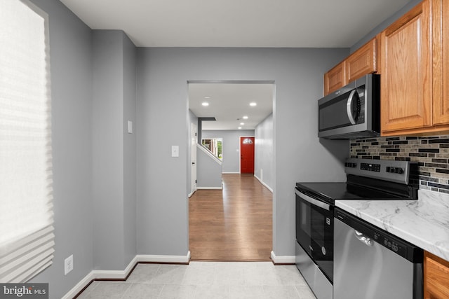 kitchen featuring stainless steel appliances, tasteful backsplash, baseboards, recessed lighting, and light stone counters