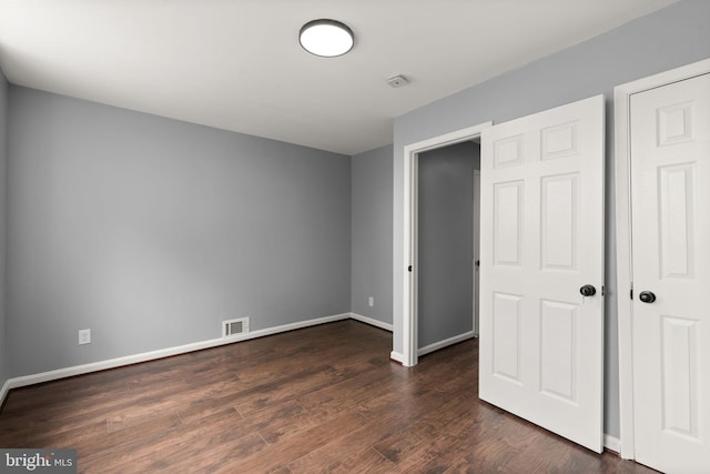 unfurnished bedroom featuring baseboards and dark wood-style flooring