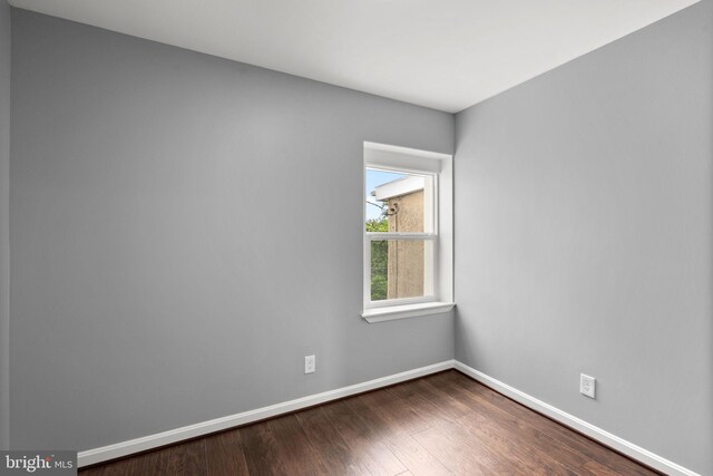 spare room with dark wood-type flooring and baseboards