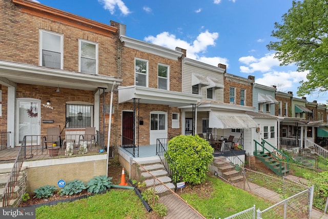 townhome / multi-family property featuring covered porch and brick siding