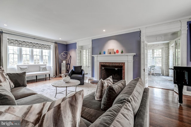 living area with a wealth of natural light, wood finished floors, a fireplace, and ornamental molding