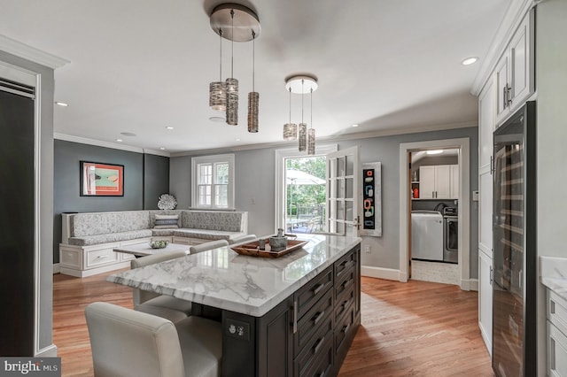 kitchen with light wood finished floors, crown molding, and washer and dryer