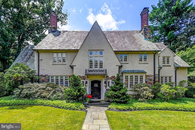 view of front of property featuring stucco siding, a chimney, and a front yard