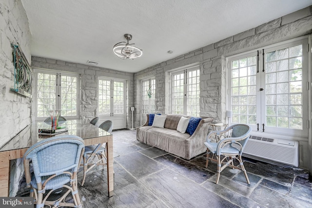 interior space with stone tile floors, a textured ceiling, a wealth of natural light, and visible vents