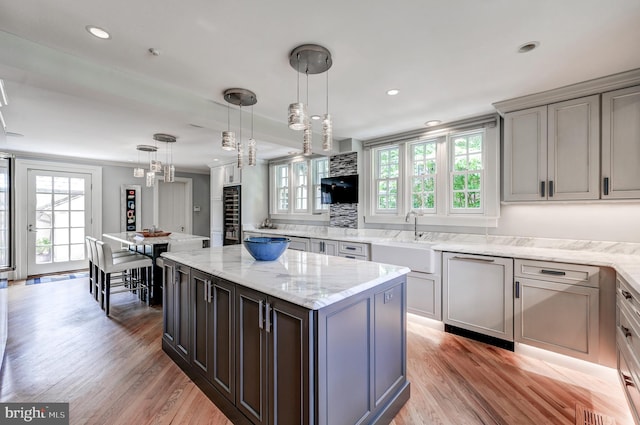 kitchen featuring recessed lighting, light wood finished floors, pendant lighting, and a sink