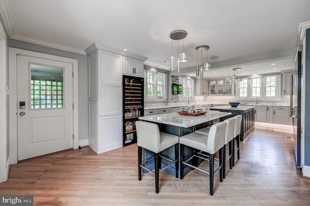 dining space with a wealth of natural light, light wood-style floors, crown molding, and beverage cooler