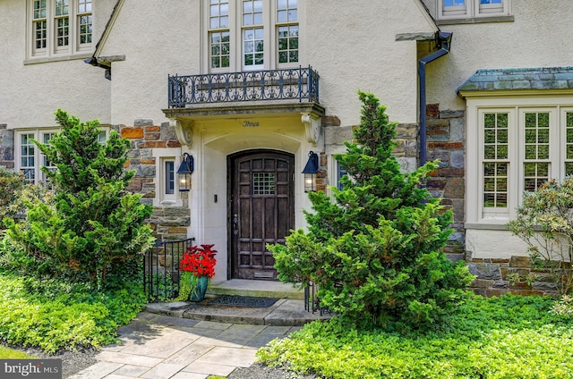 doorway to property with stone siding and stucco siding
