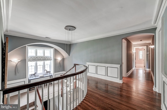 corridor with crown molding, dark wood-style flooring, an upstairs landing, and arched walkways