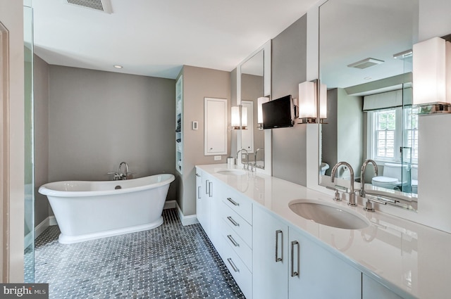 bathroom featuring a sink, a freestanding bath, double vanity, and visible vents