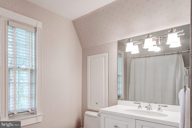 bathroom with vanity, toilet, a wealth of natural light, and wallpapered walls