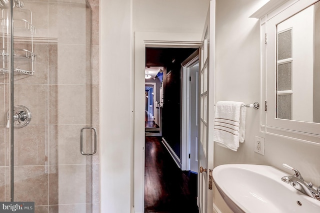 bathroom with wood finished floors, a shower stall, and a sink