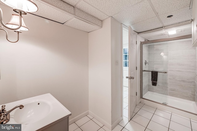 bathroom featuring a drop ceiling, a stall shower, baseboards, tile patterned flooring, and vanity