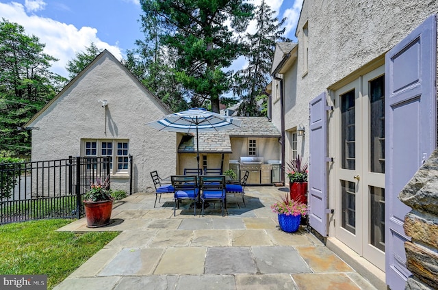 view of patio featuring french doors, outdoor dining area, and fence