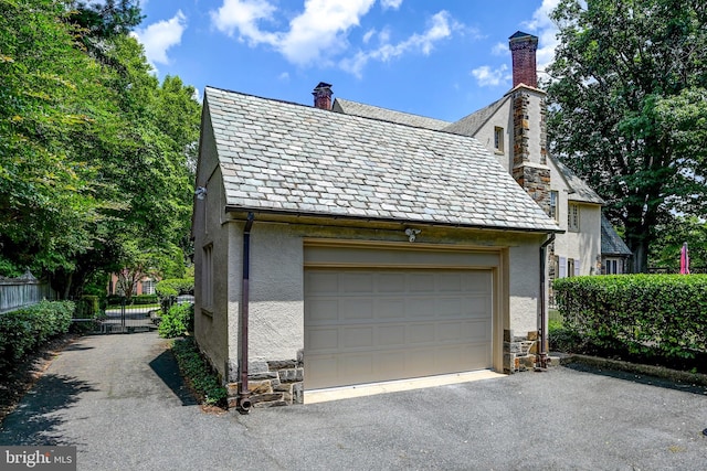 garage featuring aphalt driveway and fence