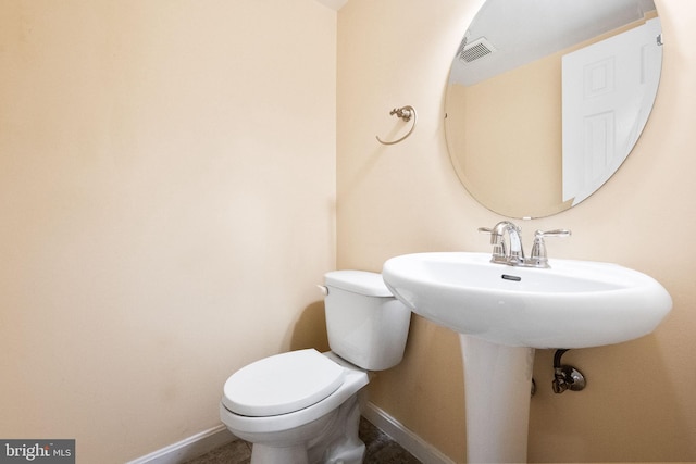 half bathroom with toilet, baseboards, and visible vents