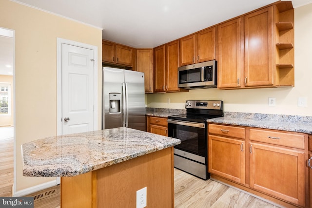 kitchen featuring open shelves, brown cabinetry, light wood-type flooring, appliances with stainless steel finishes, and a kitchen island