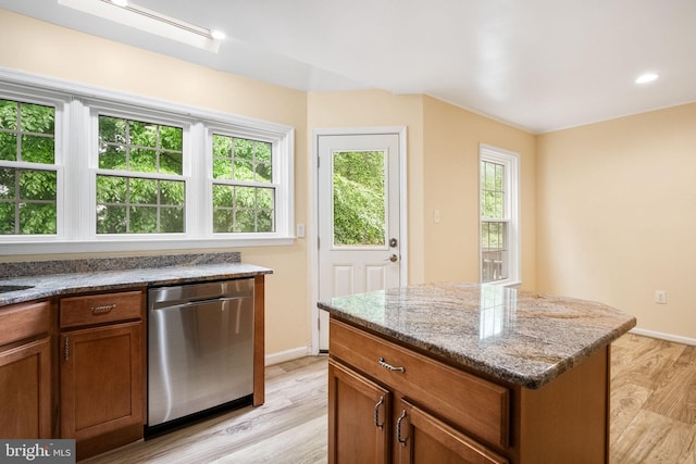 kitchen featuring baseboards, brown cabinets, light wood-style floors, and dishwasher