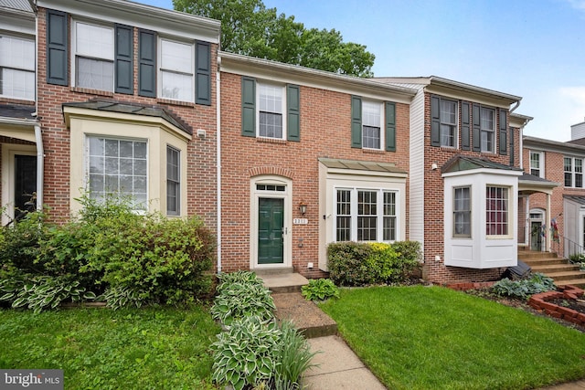 view of property featuring brick siding and a front yard