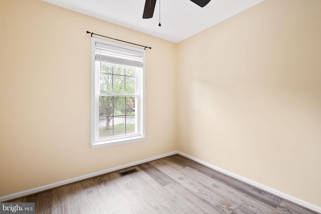 spare room featuring baseboards, visible vents, wood finished floors, and a ceiling fan