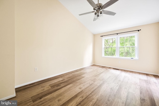 unfurnished room featuring lofted ceiling, wood finished floors, visible vents, a ceiling fan, and baseboards