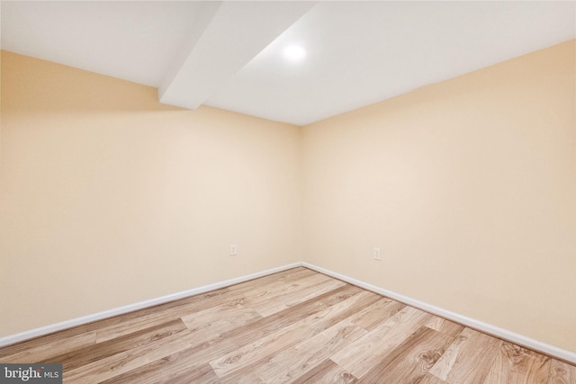 unfurnished room with baseboards, vaulted ceiling with beams, and wood finished floors