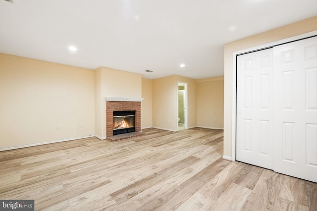 unfurnished living room featuring light wood finished floors, a brick fireplace, visible vents, baseboards, and recessed lighting