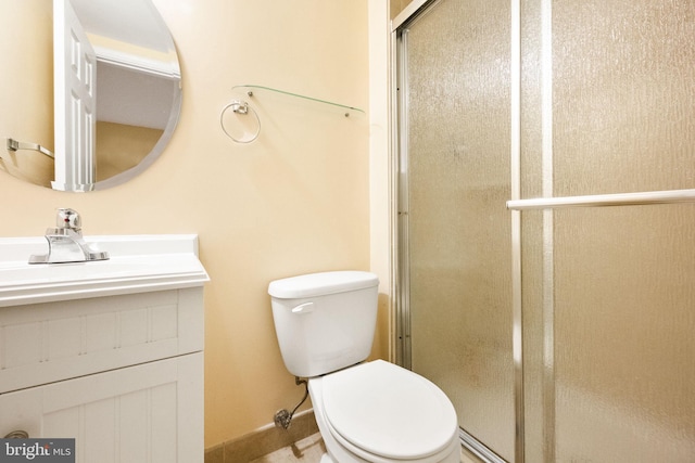 bathroom featuring vanity, toilet, baseboards, and a shower stall