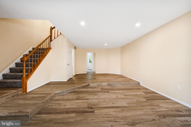 unfurnished living room with baseboards, stairs, recessed lighting, and wood finished floors