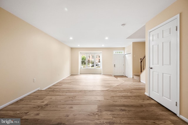unfurnished room with baseboards, light wood-style floors, recessed lighting, and stairway
