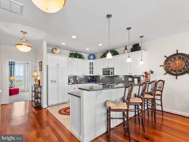 13000 Marina View Ln Unit 25, Ocean City, MD 21842 - kitchen featuring stainless steel microwave, glass insert cabinets, white cabinets, backsplash, and recessed lighting