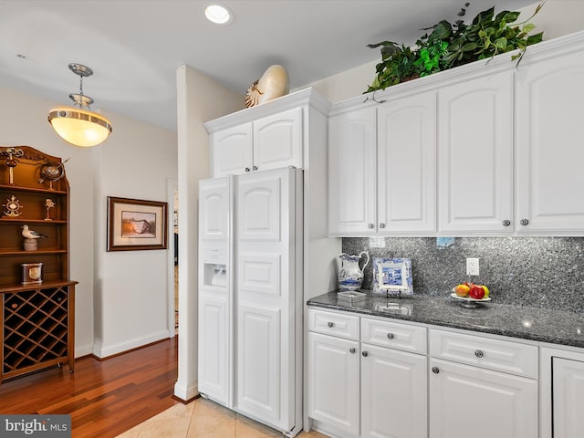 13000 Marina View Ln Unit 25, Ocean City, MD 21842 - kitchen featuring white cabinets, dark stone countertops, tasteful backsplash, baseboards, and pendant lighting