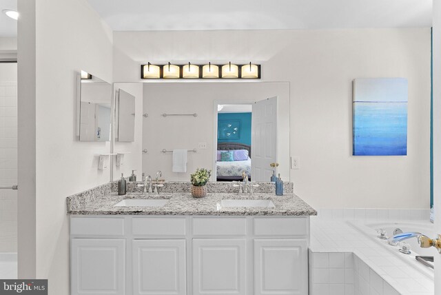 ensuite bathroom featuring a relaxing tiled tub and double vanity