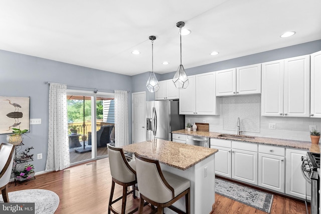 kitchen with stainless steel appliances, a sink, white cabinetry, a center island, and recessed lighting
