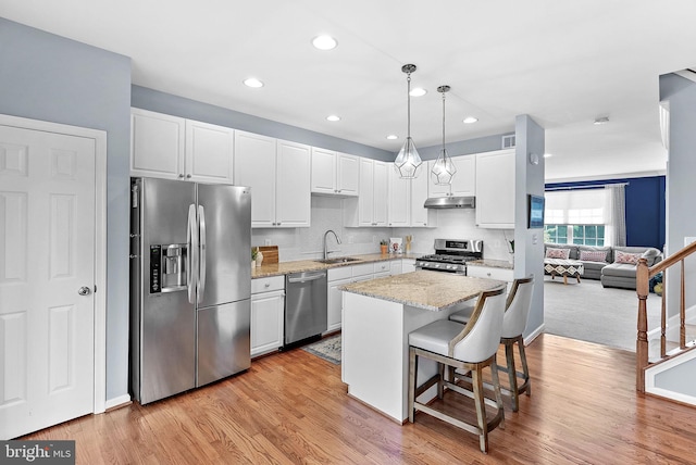 kitchen featuring stainless steel appliances, a sink, under cabinet range hood, white cabinetry, and recessed lighting