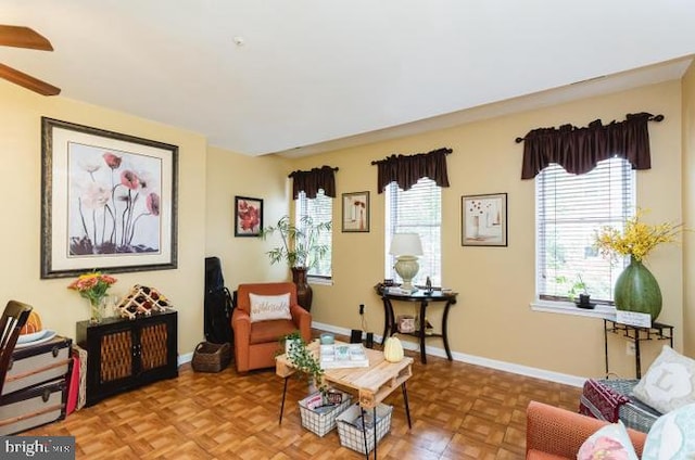 sitting room featuring a ceiling fan and baseboards