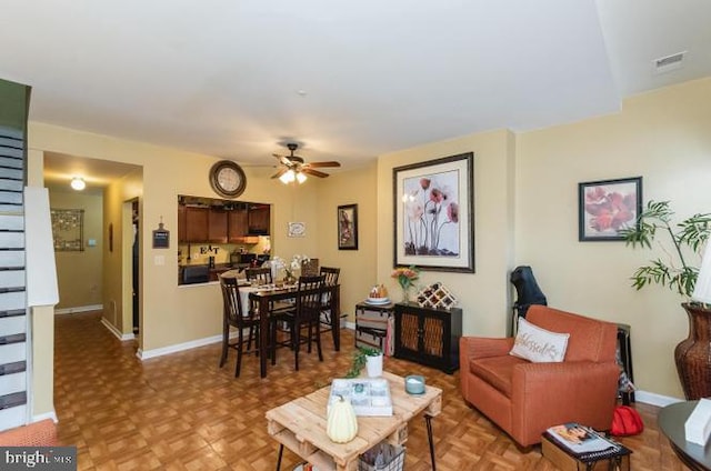 living area featuring a ceiling fan and baseboards