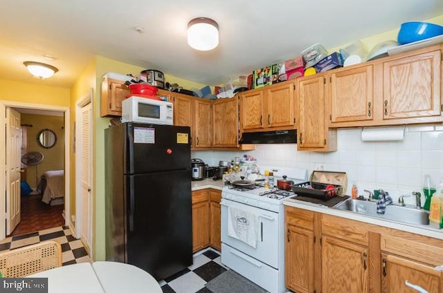 kitchen featuring white appliances, tile patterned floors, a sink, under cabinet range hood, and light countertops