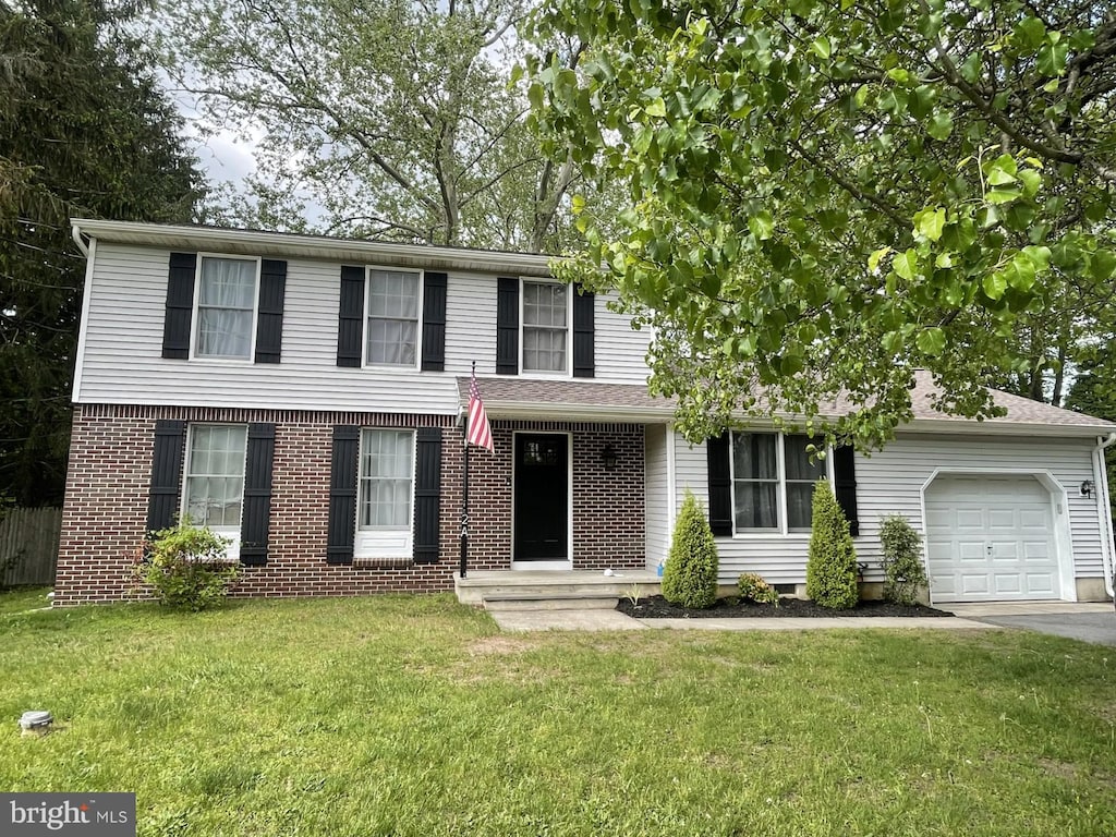 traditional-style house featuring a front lawn, driveway, brick siding, and a garage