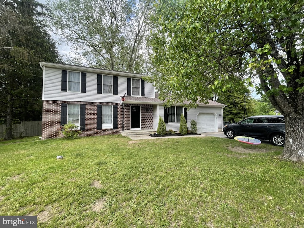 traditional home with a front yard, brick siding, fence, and a garage