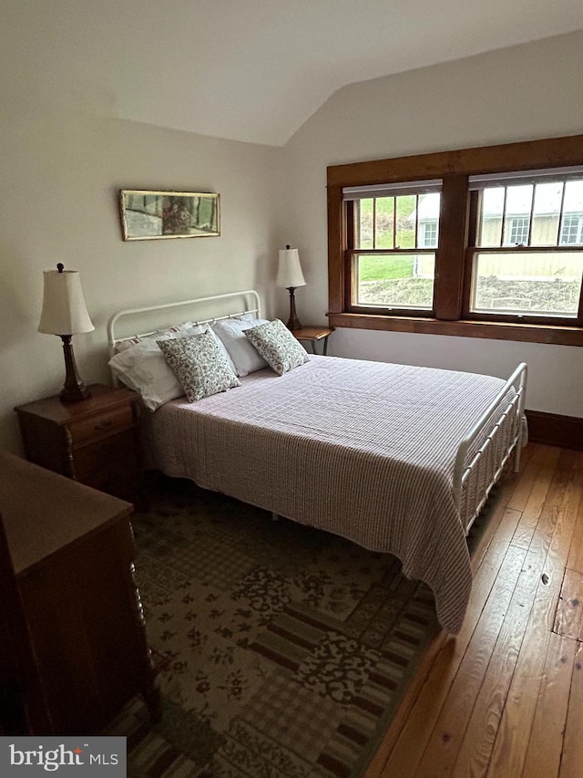 bedroom with lofted ceiling and dark wood-style floors