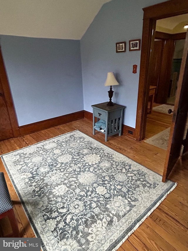 interior space with lofted ceiling, baseboards, and wood finished floors